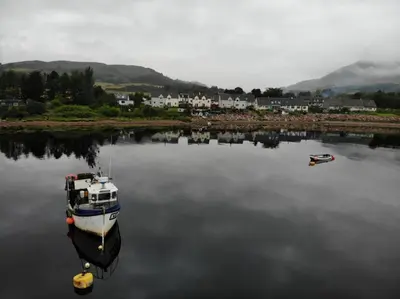 a boat in a body of water with a small boat at Maggie's in Inveraray