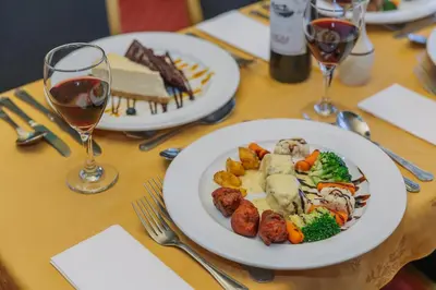 a table with two plates of food and glasses of wine at Muthu Ben Doran Hotel in Tyndrum