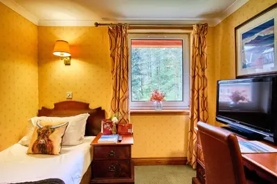 a bedroom with a bed and a cat sitting on a table at Muthu Ben Doran Hotel in Tyndrum