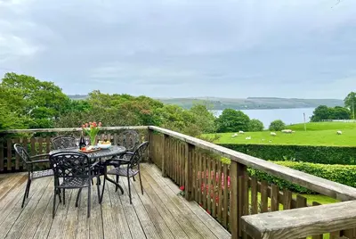 a table and chairs on a deck with a view of a field at Alder Cottage in Blairmore