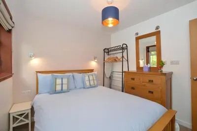 a bedroom with a bed and a dresser and a mirror at Alder Cottage in Blairmore