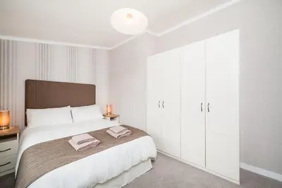 a bedroom with a large bed with white cabinets at Thistle Lodge in Auchterarder