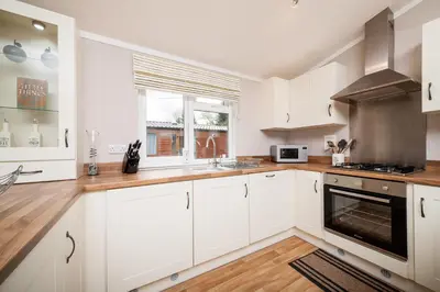 a kitchen with white cabinets and a window at Thistle Lodge in Auchterarder