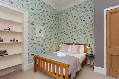a bedroom with a bed with floral wallpaper at South Learmonth Gardens Apartment in Edinburgh