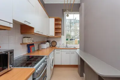 a kitchen with white cabinets and a stove top oven at South Learmonth Gardens Apartment in Edinburgh