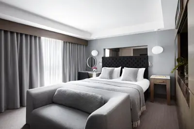 a bedroom with a large bed and a chair at Kimpton Blythswood Square Hotel & Spa by IHG in Glasgow