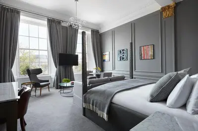 a bedroom with a king sized bed and a living room at Kimpton Blythswood Square Hotel & Spa by IHG in Glasgow