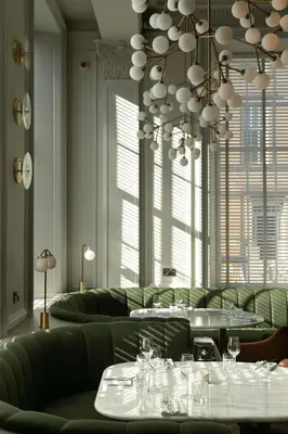 a dining room with green furniture and a chandelier at Kimpton Blythswood Square Hotel & Spa by IHG in Glasgow