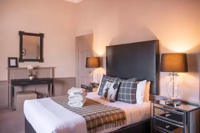 a bedroom with a bed and a desk with two lamps at The Allan Park in Stirling