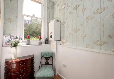 a room with a chair and a window with wallpaper at The Lauderdale Street Residence in Edinburgh