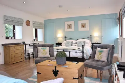 a bedroom with a bed and two chairs and a table at Cobbler's Cottage in Dunblane