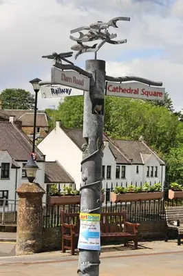 a pole with street signs on it with buildings at Cobbler's Cottage in Dunblane