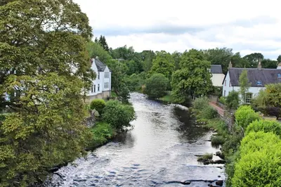a river in a town with houses and trees at Cobbler's Cottage in Dunblane