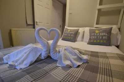 two towel swans sitting on top of a bed at Slateford House Apartment Ground Floor Main Door in Edinburgh