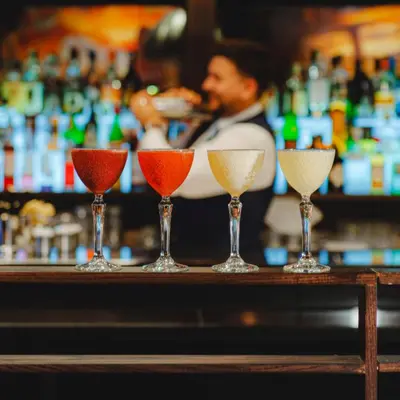 four wine glasses sitting on a bar with a bartender at Dakota Edinburgh in Queensferry