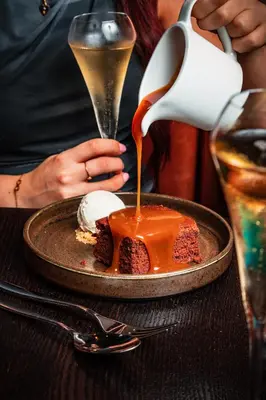 a person is pouring caramel sauce on a dessert at Dakota Edinburgh in Queensferry