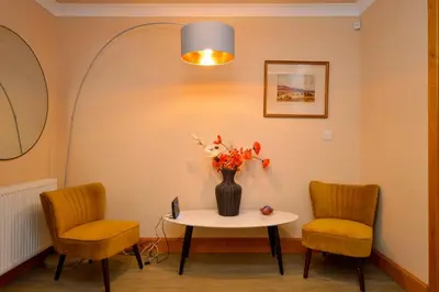 a room with two chairs and a table with a vase of flowers at Taigh na Mara in Kames