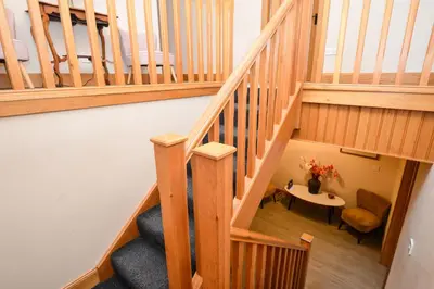 a wooden staircase with a table and a chair at Taigh na Mara in Kames