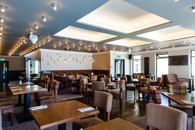 a restaurant with tables and chairs in a room at Adamson Hotel in Dunfermline