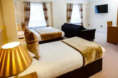 a hotel room with two beds and a television at Adamson Hotel in Dunfermline