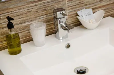 a bathroom sink with a bottle of soap and a faucet at Adamson Hotel in Dunfermline