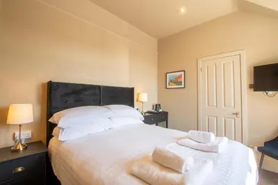 a bedroom with a large white bed with towels on it at Dalrigh House in Oban