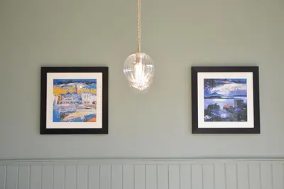 three framed pictures on a wall with a chandelier at Dalrigh House in Oban