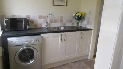 a kitchen with a sink and a washing machine at Aird Farm Holiday Cottages in Ardfern