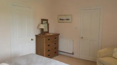 a bedroom with a dresser and a mirror and a bed at Aird Farm Holiday Cottages in Ardfern