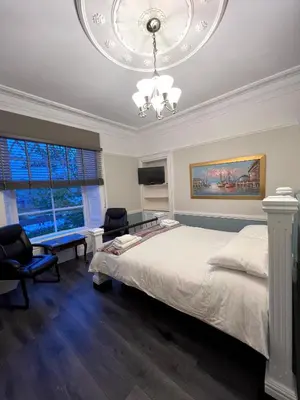 a bedroom with a large bed and a chandelier at Ivybank Villa in Rothesay