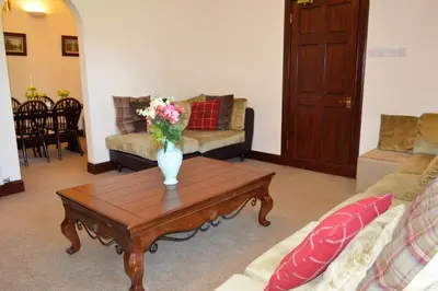 a living room with a vase of flowers on a coffee table at Culzean House in Ardentinny