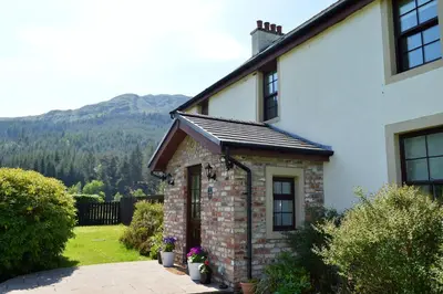 a brick house with a mountain in the background at Culzean House in Ardentinny