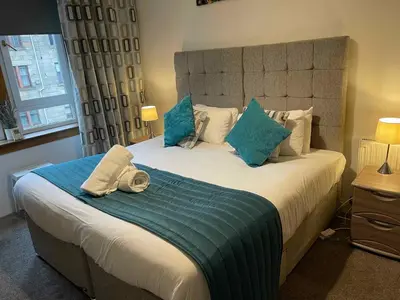 a bedroom with a large bed with blue pillows at Scotstoun Appartments in Glasgow