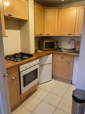 a kitchen with white appliances and wooden cabinets at Scotstoun Appartments in Glasgow