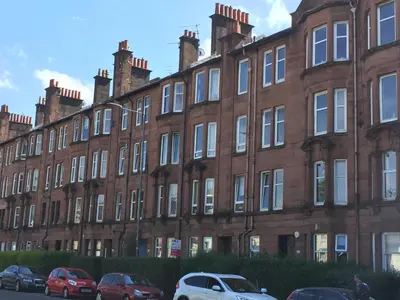 a large brick building with cars parked in front at Scotstoun Appartments in Glasgow