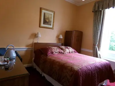 a bedroom with a bed and a dresser and a window at Averon Guest House in Edinburgh