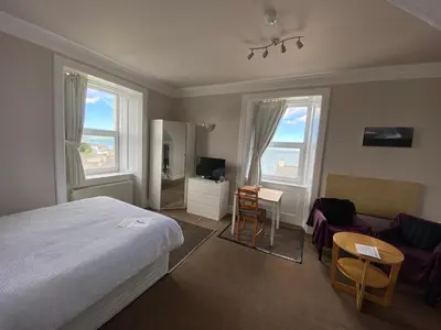 a bedroom with a bed and a table and chairs at The Bowmore House Bed and Breakfast in Bowmore