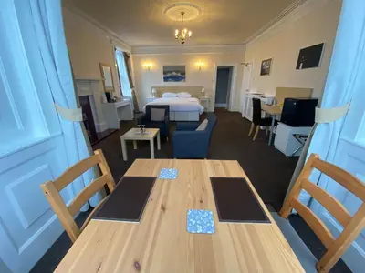 a room with a bed and a table and chairs at The Bowmore House Bed and Breakfast in Bowmore