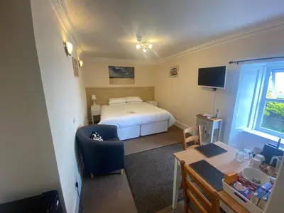 a bedroom with a bed and a chair and a desk at The Bowmore House Bed and Breakfast in Bowmore