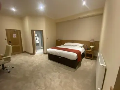 a bedroom with a bed and a desk and a chair at The City Hotel in Dunfermline