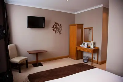 a hotel room with a bed and a desk and a television at The City Hotel in Dunfermline