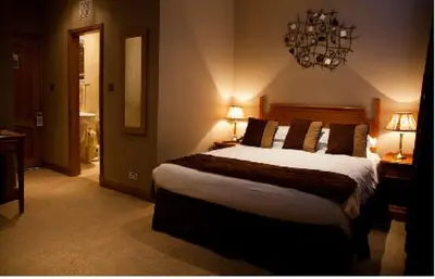 a bedroom with a large bed and a chandelier at The City Hotel in Dunfermline