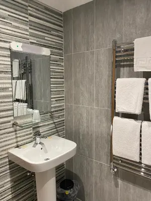 a bathroom with a sink and a mirror and towels at The City Hotel in Dunfermline