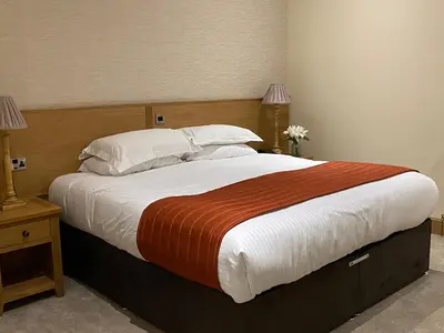 a bedroom with a large bed with white sheets and pillows at The City Hotel in Dunfermline