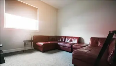 a living room with a brown leather couch and a window at Cunninghame 1 in Beith