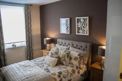 a bedroom with a bed with pillows and a window at Lexington Apartments in Rothesay