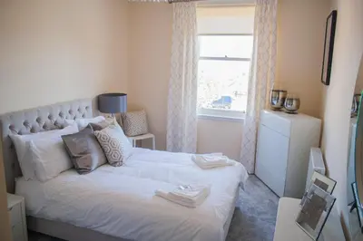a bedroom with a white bed with a window at Lexington Apartments in Rothesay