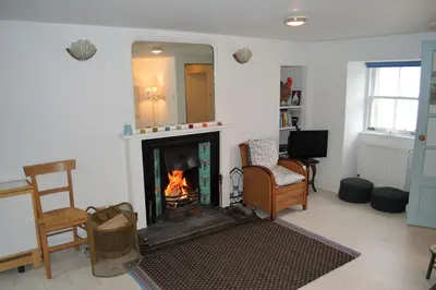 a living room with a fireplace and a mirror at Newton Cottage North in Inveraray
