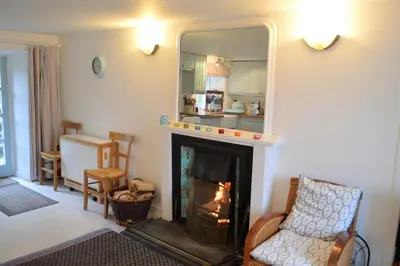 a living room with a fireplace and a mirror at Newton Cottage North in Inveraray