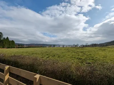 a field with a fence and a cloudy sky at The Manor Sea View 8 in Dunoon